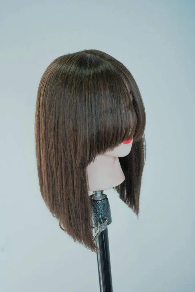 Mannequin head with realistic brown long straight hair against a gray background.